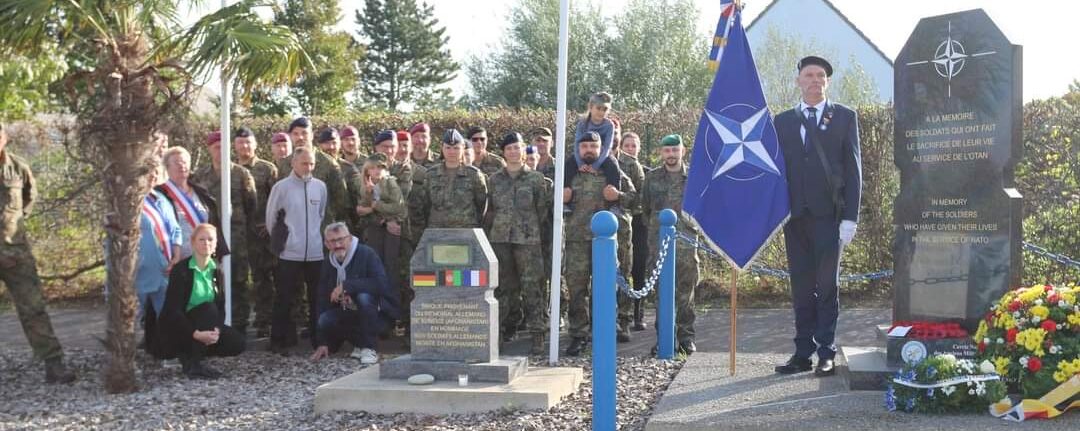 Gedenkveranstaltung mit Soldaten und Zivilisten vor einem Denkmal, um die gefallenen Soldaten zu ehren.